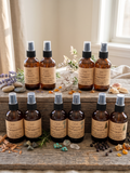 Aromatherapy Room and Linen Sprays in amber bottles displayed on rustic barnwood scene. Michigan Made. Small Batch. Spirit Led Creative. 
